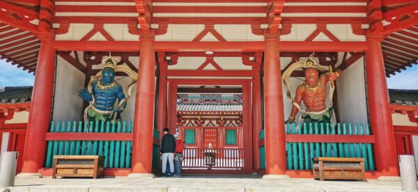 La porte d'entrée d'un temple qui dispose 2 grands guerriers rouge et bleu de chaque côté.